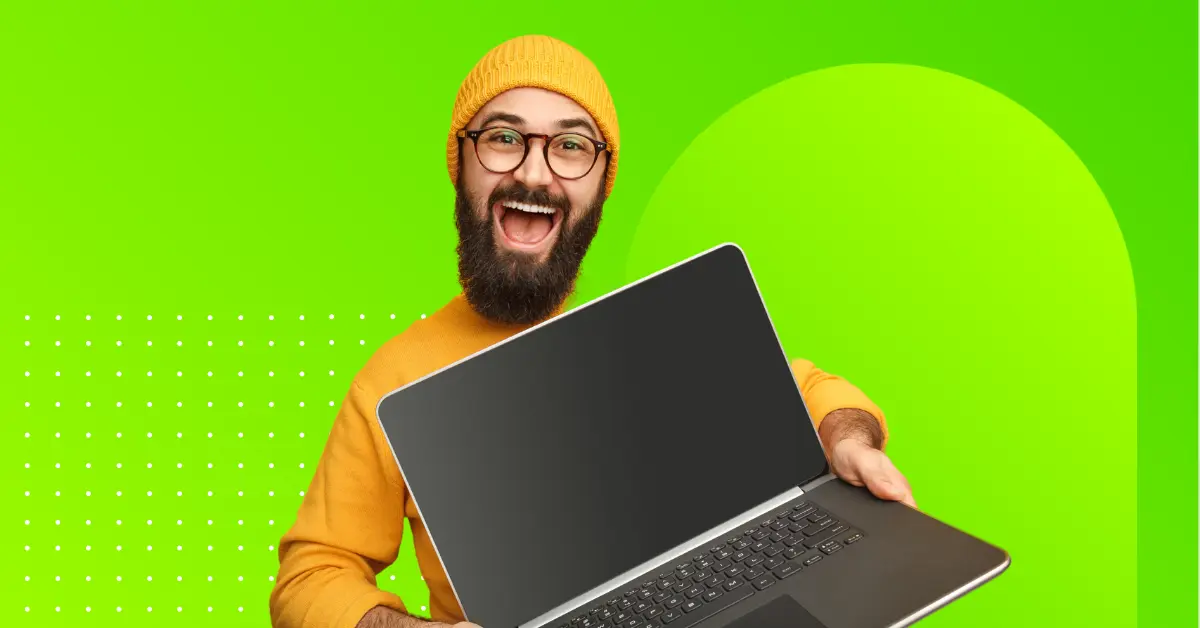 Man with a wide smile, holding a laptop.