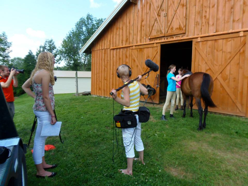 White Knight crew members capturing video and sound at a horse stable.