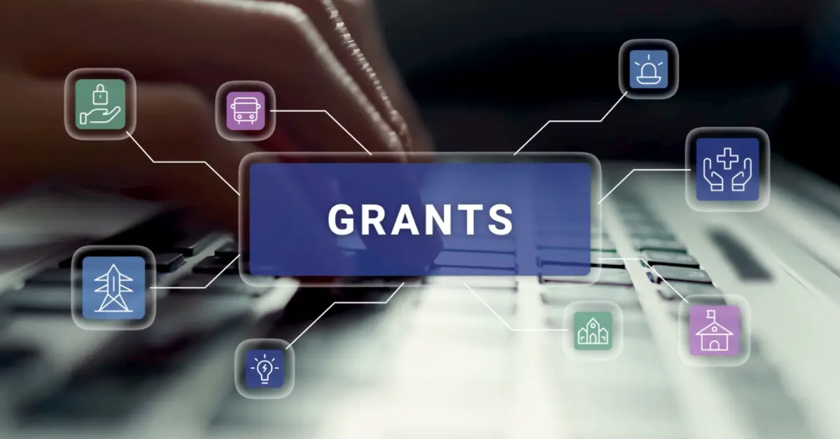 A variety of industry icons spread out from a central graphic that says Grants. Hands type on a keyboard in the background.
