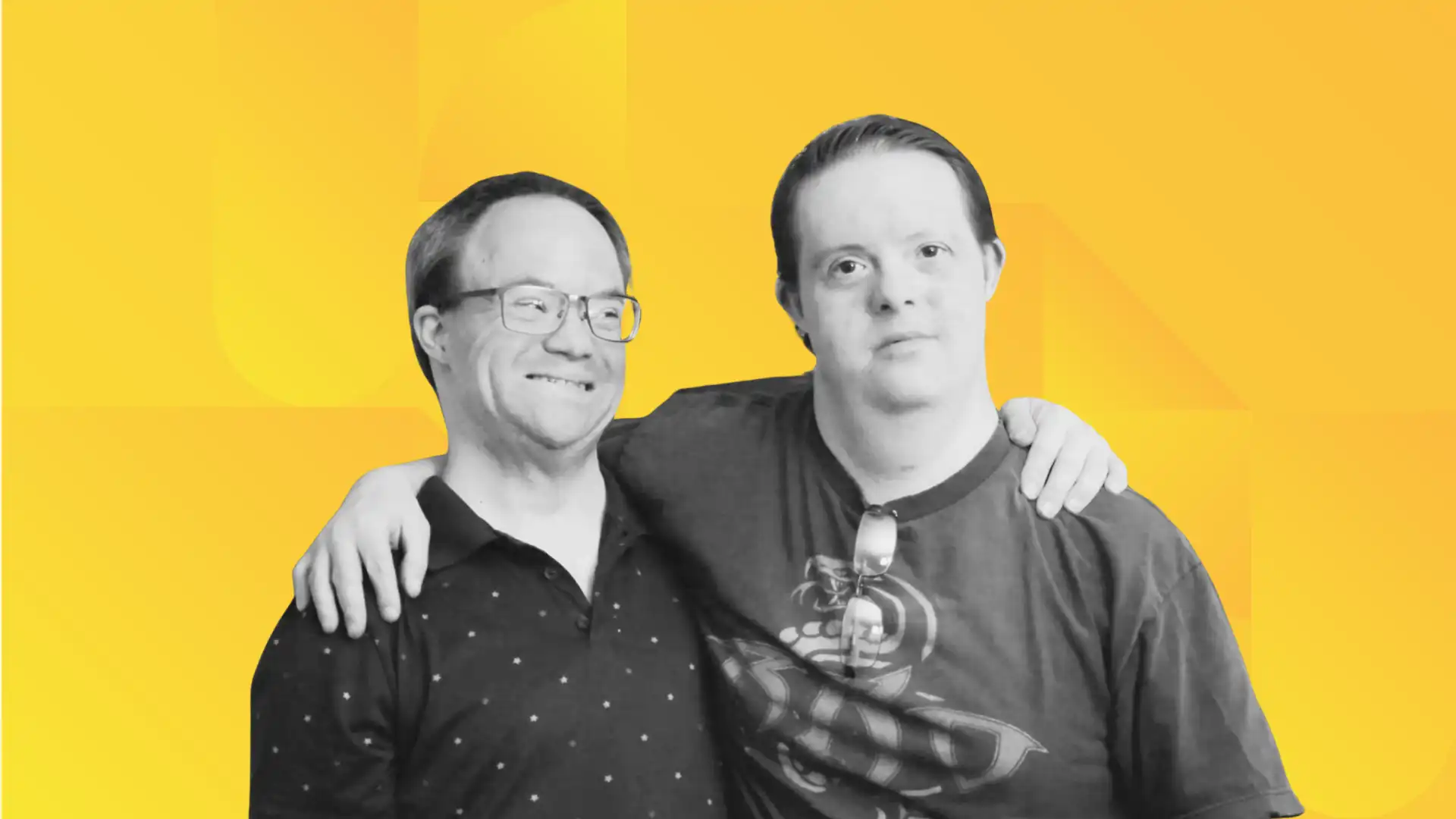 Two people with visible disabilities stand together with their arms around each other’s shoulders, smiling.